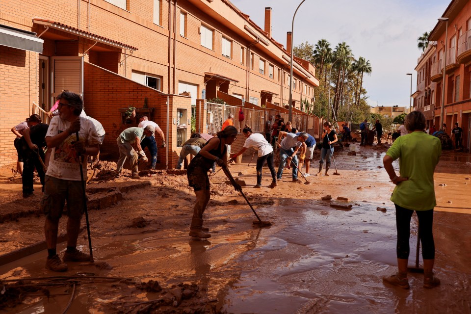 Volunteers and locals help to clean the street following the floods