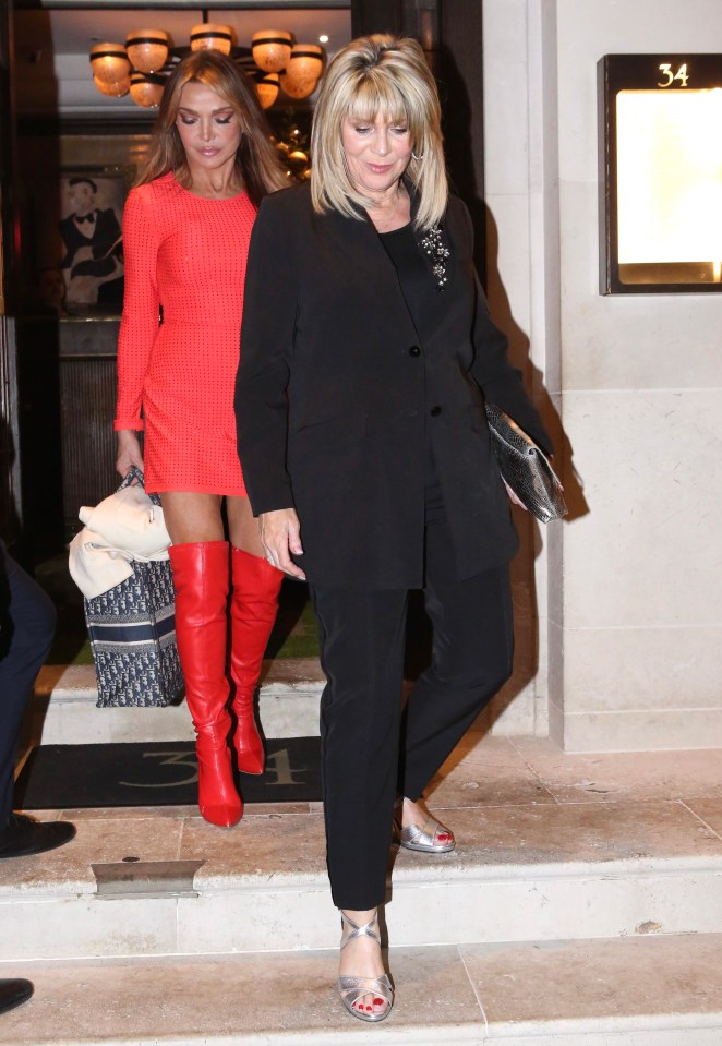 a woman in a red dress and red boots stands next to a woman in a black suit