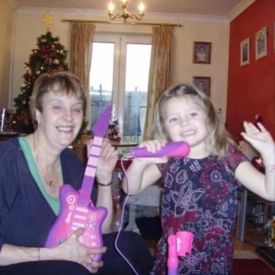 a little girl is singing into a microphone while holding a pink guitar