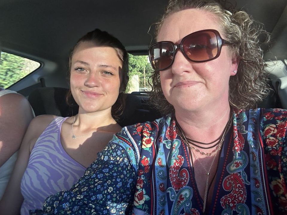 a woman wearing sunglasses sits next to another woman