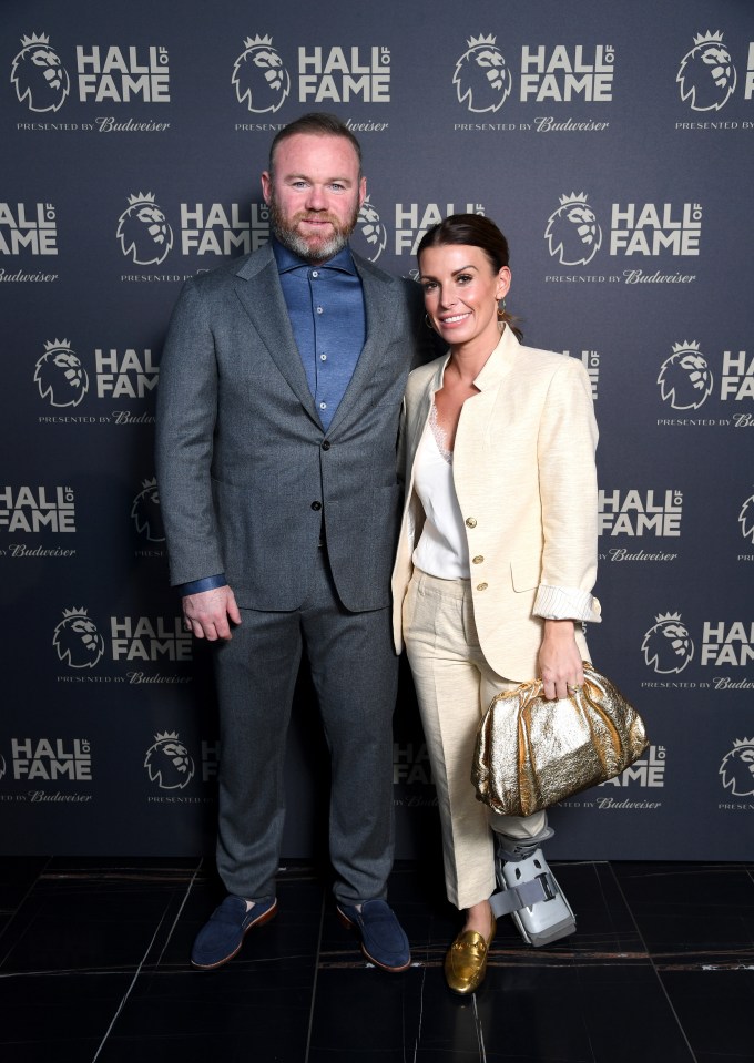 a man and woman pose in front of a wall that says hall of fame