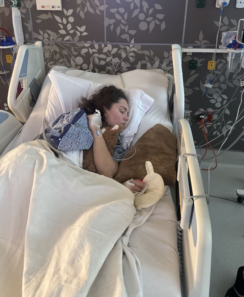 a woman is laying in a hospital bed holding a teddy bear