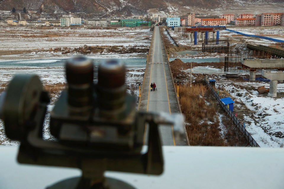 Women, photographed from the Chinese side of the border, cross the bridge from Namyang in North Korea towards the town of Tumen