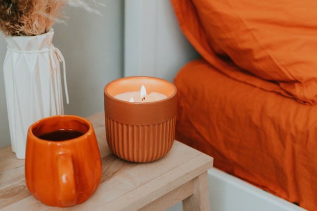 a candle sits on a table next to an orange mug