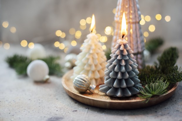 three lit candles in the shape of christmas trees on a wooden tray