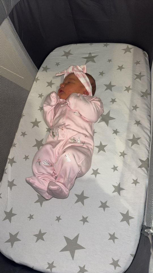 a baby in a pink outfit is laying on a blanket with stars on it