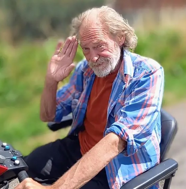 a man in a plaid shirt is sitting on a scooter and waving