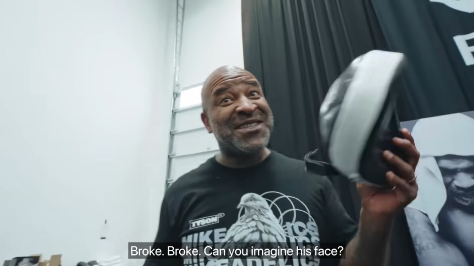 a man wearing a mike tyson shirt is holding a shoe