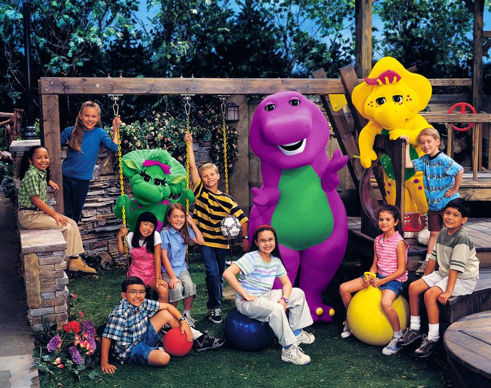 Barney the dinosaur with a young Selena Gomez (on yellow ball) and Demi Lovato an American singer and actress (wearing glasses and red headband)