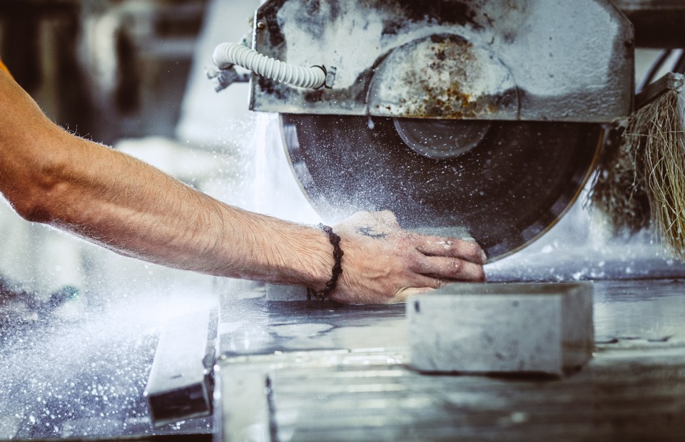 a man wearing a bracelet is using a machine to cut a piece of metal