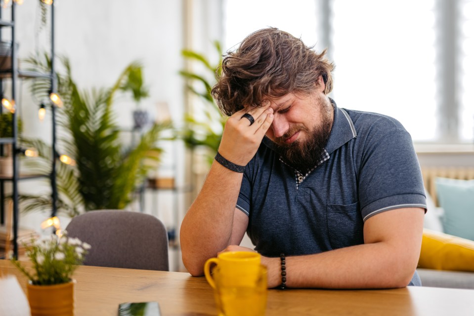 a man sitting at a table with his hand on his forehead