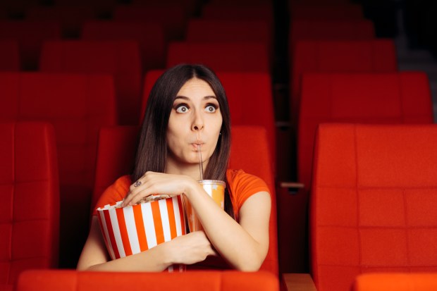 a woman is eating popcorn in a movie theater