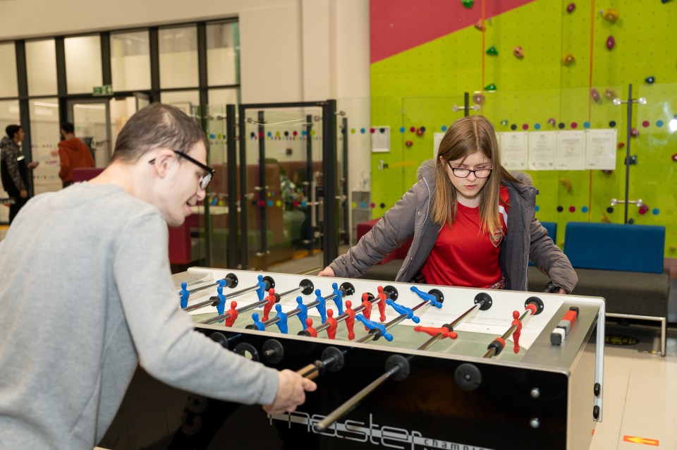 a man and a girl are playing a game of foosball on a table that says neaster on it