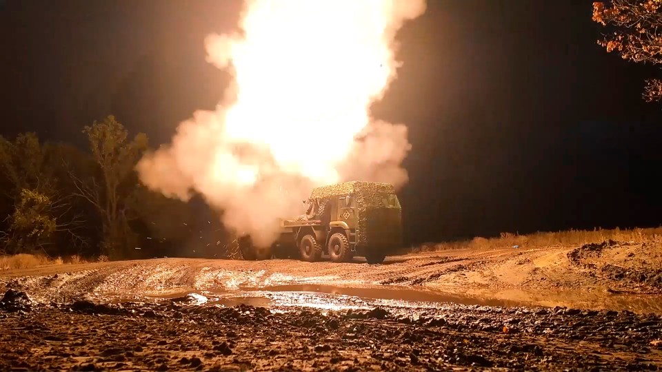 a military vehicle is driving down a dirt road at night