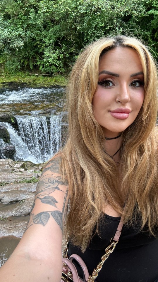 a woman taking a selfie in front of a waterfall