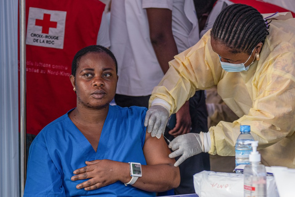 A medical staff receives a vaccine for smallpox and mpox