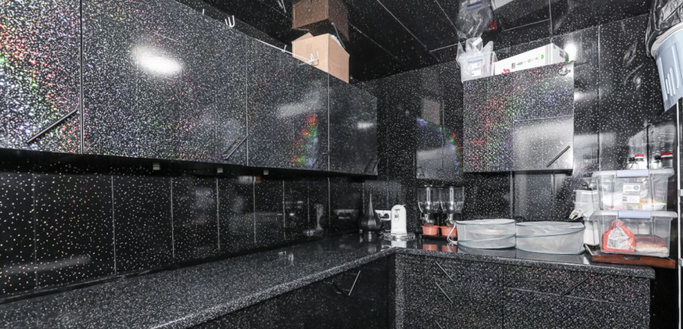 The kitchen features black glittery walls and units