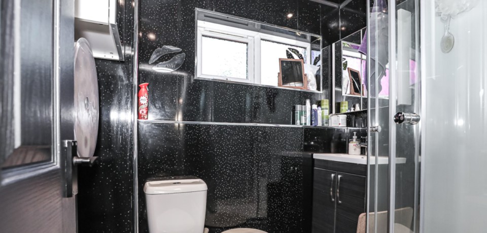 The bathroom shares the same black glittery finishing as the kitchen