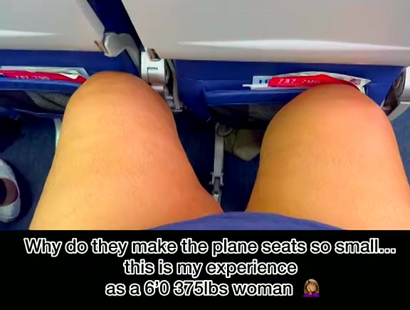 A plus-size woman's legs overflowing a standard airplane seat.