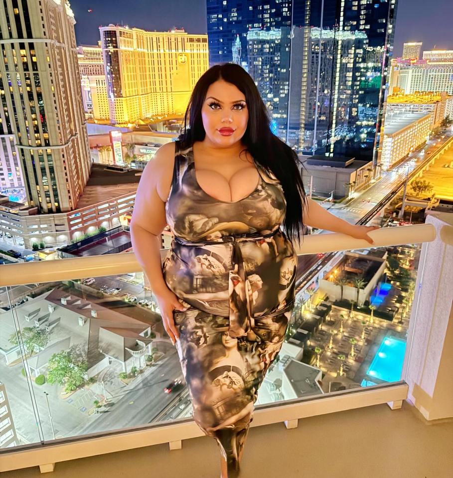 Plus-size influencer posing on a balcony overlooking a city at night.