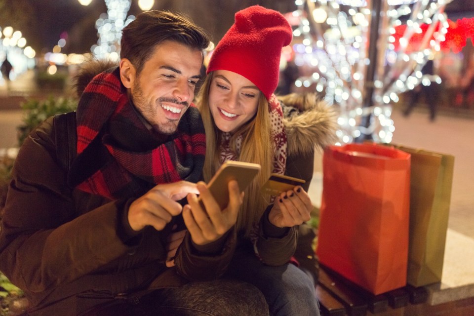 Couple Christmas online shopping using smartphone and credit card.