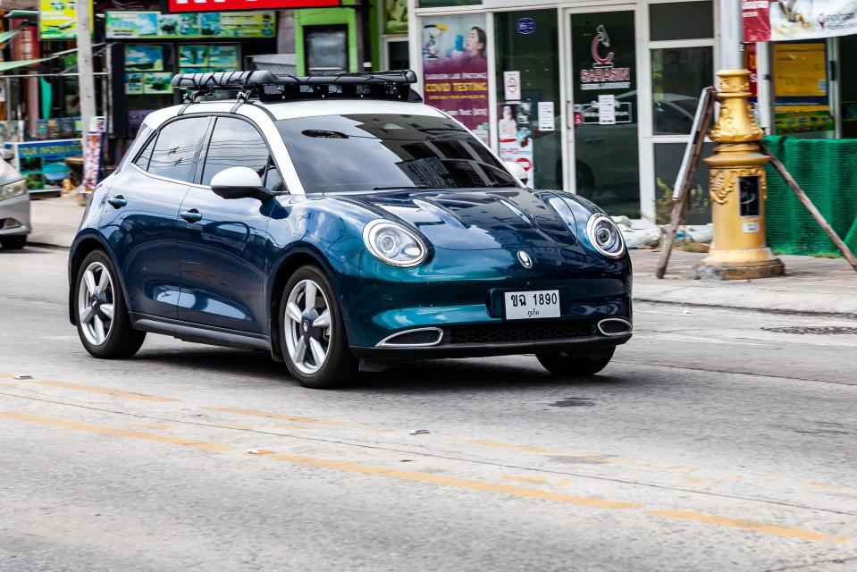 Blue Ora Funky Cat electric car driving on a road.