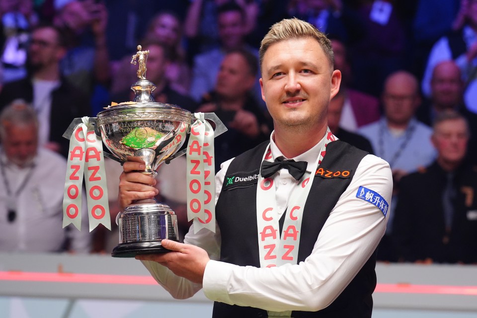 Kyren Wilson holding the World Snooker Championship trophy.