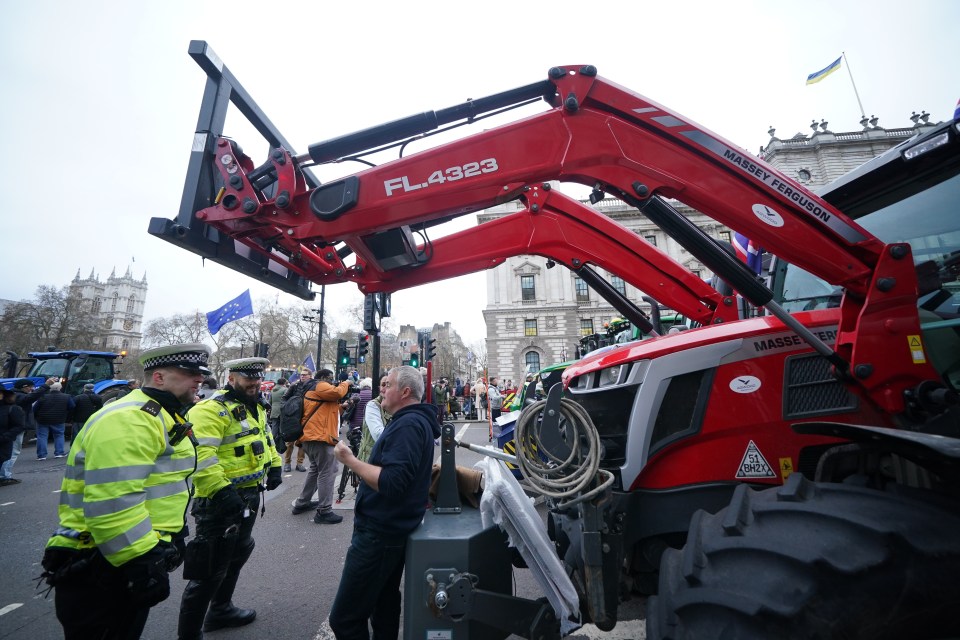 Police officers stand ahead of the tractors