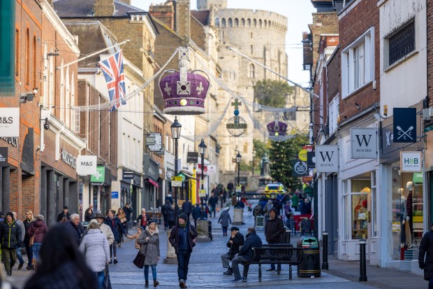 Windsor high street with shoppers and shops, including M&amp;S and Waterstones, with Windsor Castle in the background.