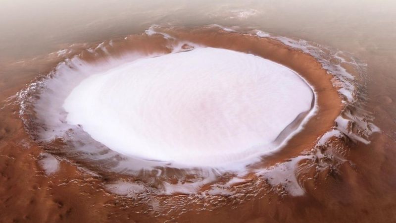 If you're good at ice skating, you'd probably be tempted to try out your skills on this breathtaking sheet of ice. The only problem is...the lack of oxygen in the atmosphere! That's because this photo was taken on Mars by the European Space Agency's Mars Express spacecraft. The newly released image from the European Space Agency has been put together from five different 'strips' combined to form a single image, with each strip gathered over a different orbit. This ice-filled crater is called the Korolev crater - it's is 82 kilometres in length and is found in the northern lowlands of Mars. You certainly wouldn't be in any danger of falling through the surface. The ice is more than 1,799 metres thick all year long. It's not just there over the Martian winter either! Due to something called the 'cold trap' phenomenon, the ice is a permanent fixture on the planet. With ice on the base of the crater floor, more than a mile below the rim, it acts as a cold trap from below. Air moving over the ice from above cools and sinks, creating a layer of cold air over the ice. This means the ice doesn't melt. Mars-vellous!