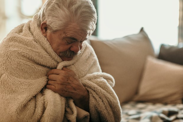 Sick elderly man wrapped in a blanket.