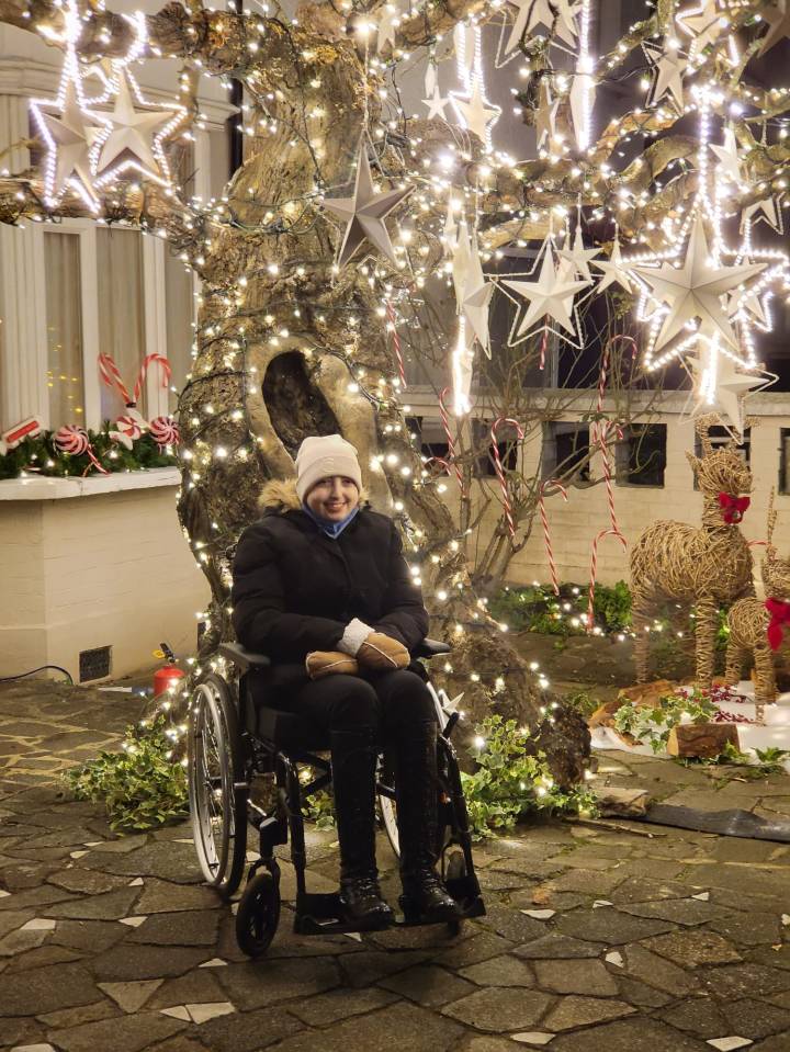 Ellie Inglis all smiles next to the Make-A-Wish Foundation tree at her family home