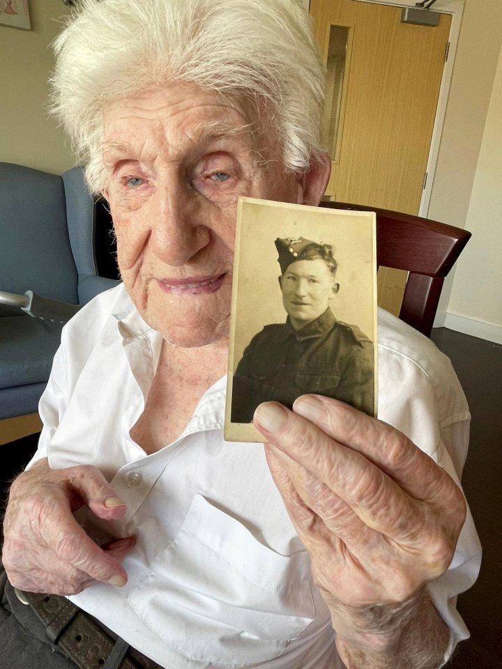 A 108-year-old World War II veteran holds a photo of his younger self in uniform.