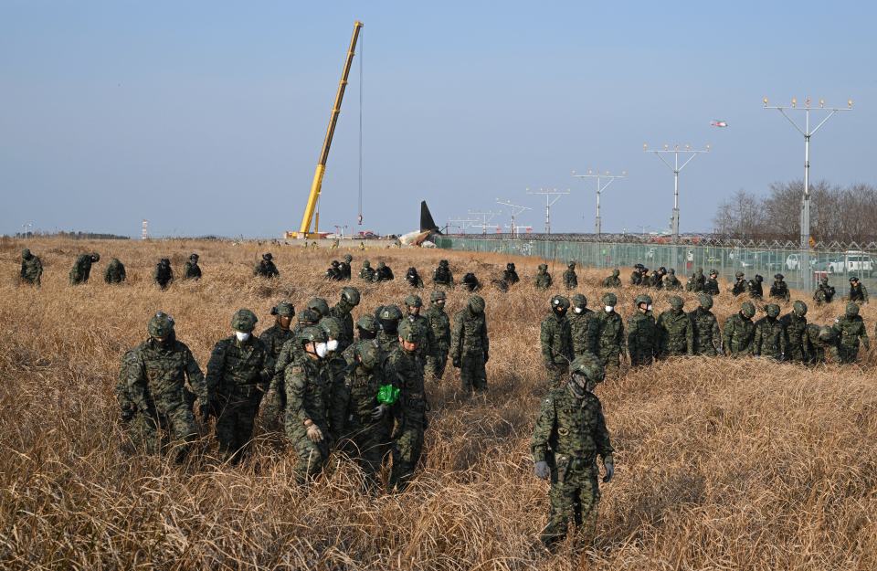 South Korean soldiers searching for victims near a crashed airplane.