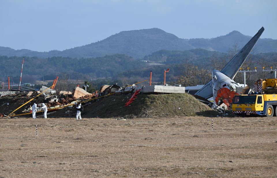 Debris from a plane crash at Muan International Airport with recovery teams working at the scene.