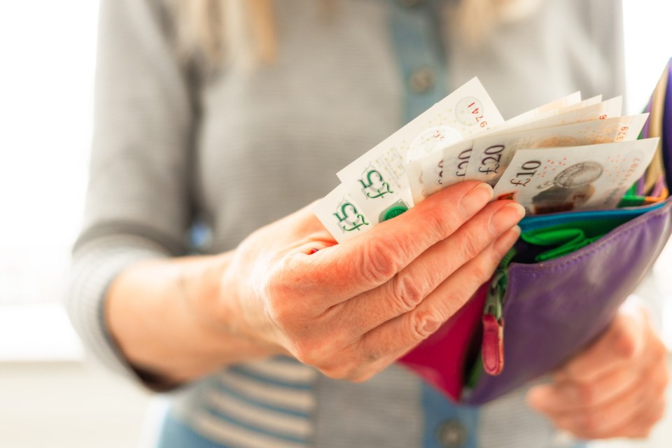 A senior woman taking British banknotes from her wallet.