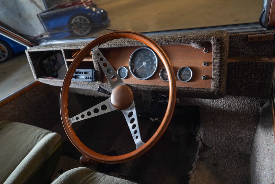 Wooden steering wheel and dashboard of a classic car.