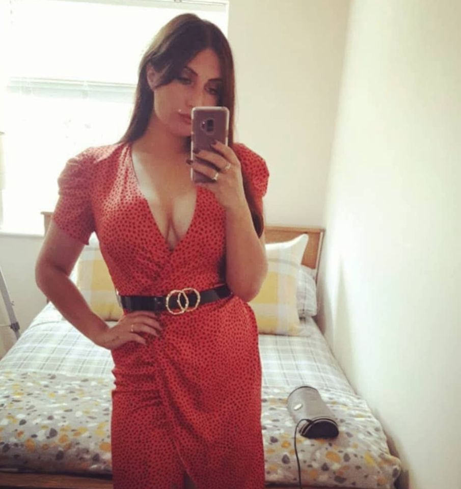 Woman taking a selfie in a red dress after breast augmentation surgery.