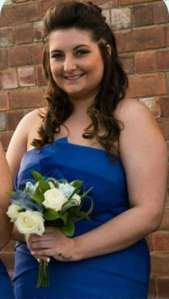 Woman in blue dress holding a bouquet of white roses.