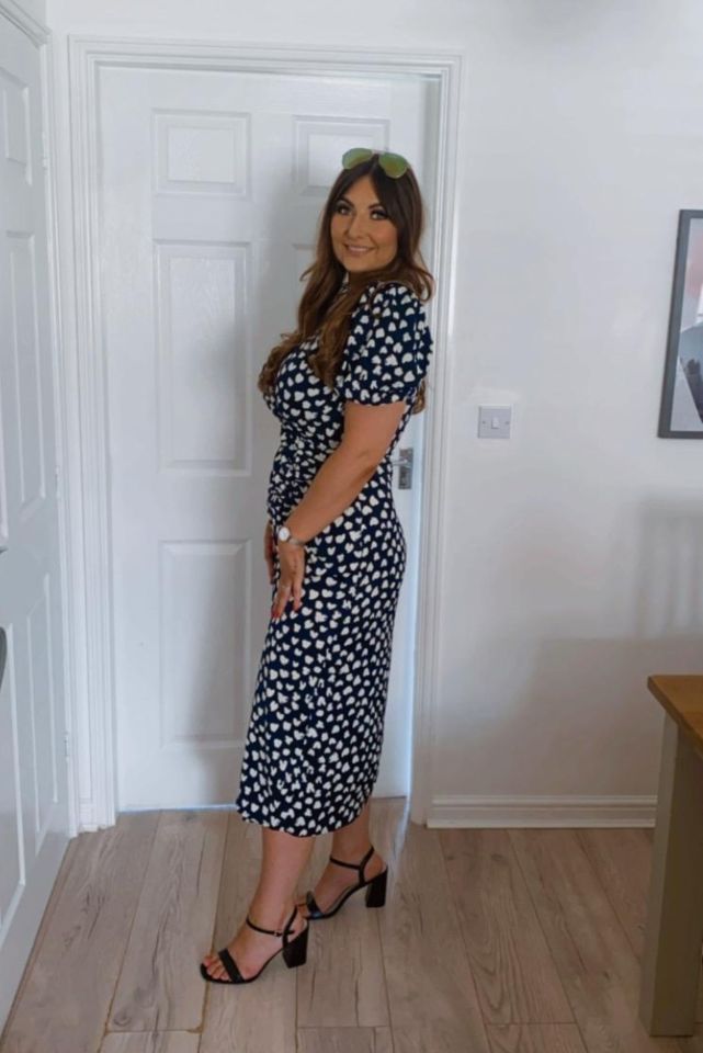 Woman in a navy and white heart print dress and black heels.