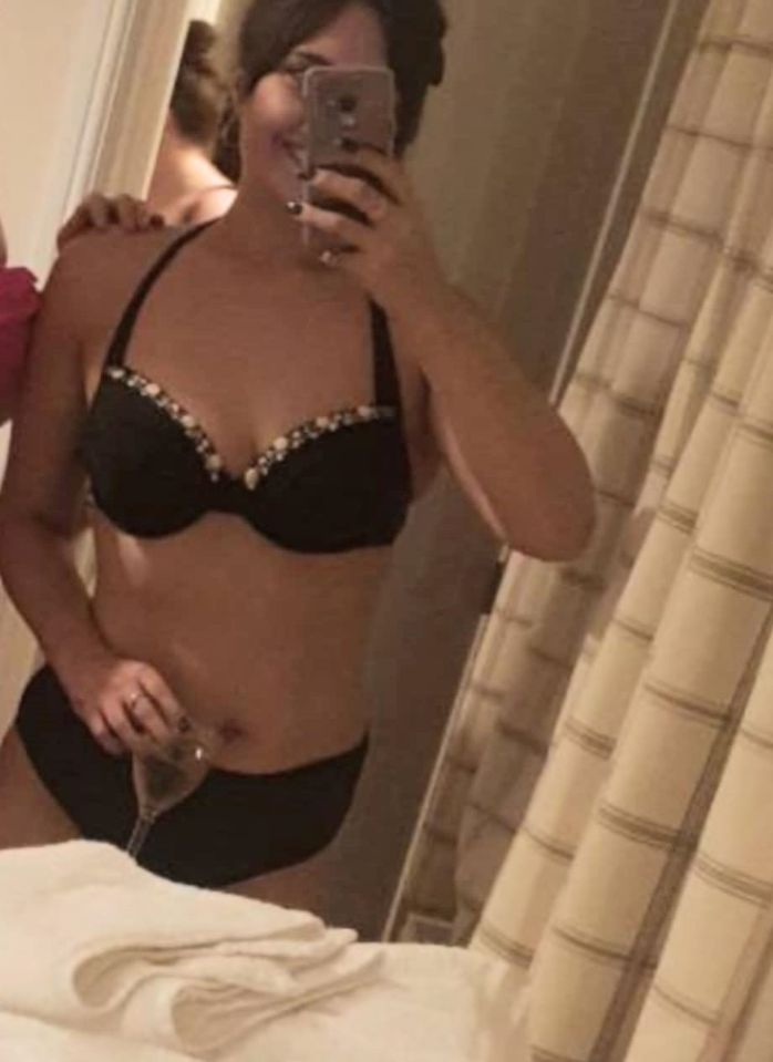 Woman in black bikini top and bottom taking a selfie.