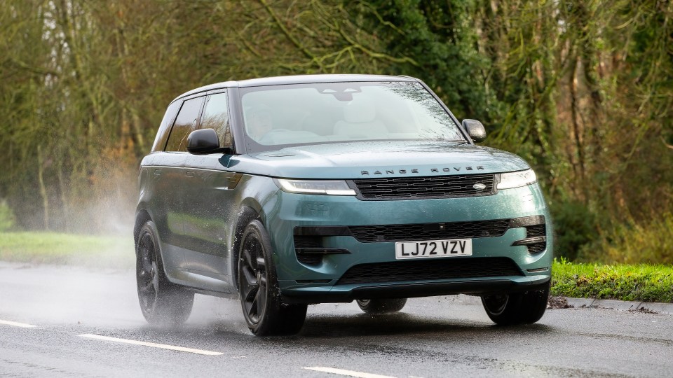 Green Range Rover Sport driving on a wet road.