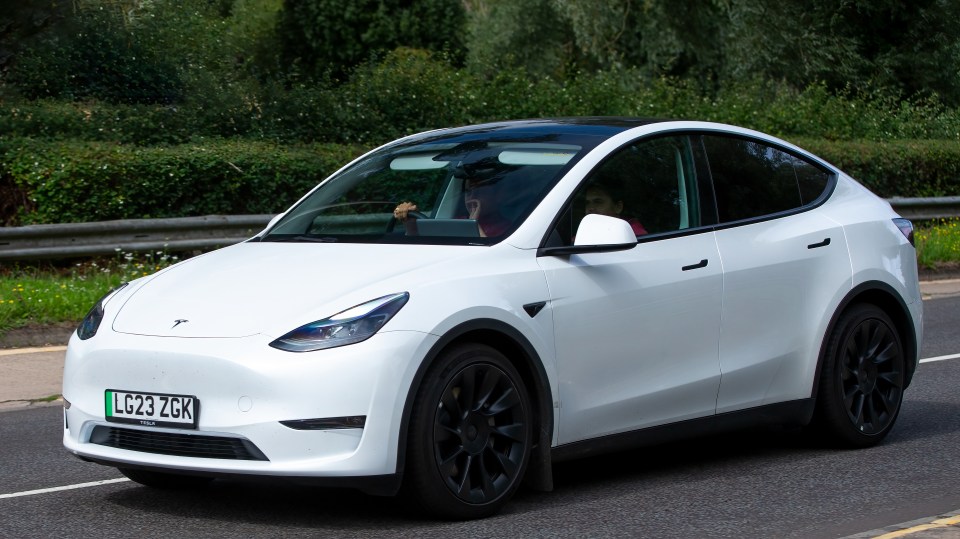 White Tesla Model Y driving on a road.