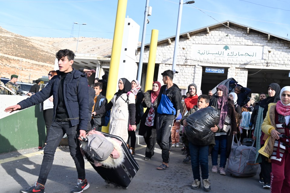 People, including Syrian citizens, walk with their belongings after they arrived from Syria, at the Al-Masnaa crossing on the Lebanese-Syrian border