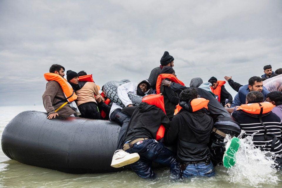 Migrants attempt to board a smuggler’s inflatable dinghy in an attempt to cross the English Channel, on October 30