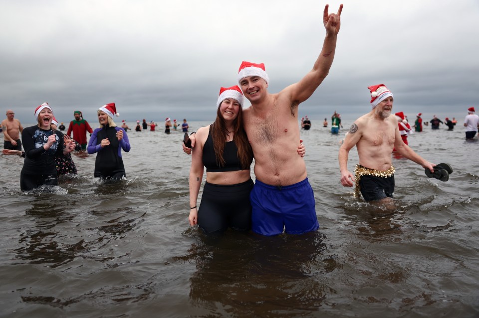 People in Santa hats participate in a charity Boxing Day swim.