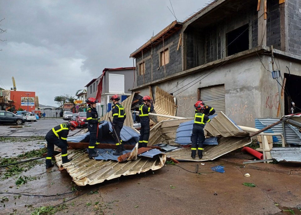 Rescue workers clean up what appears to be a roof blown off a house as the cyclone hit