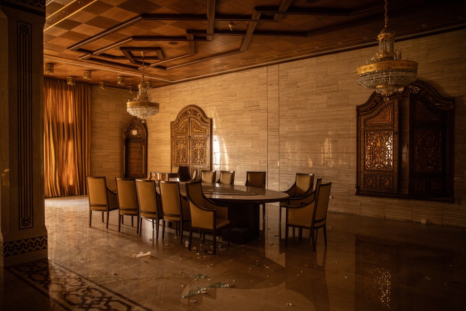 Looted room in Bashar al-Assad's Tishreen Palace in Damascus, Syria, showing damaged furniture and a conference table.