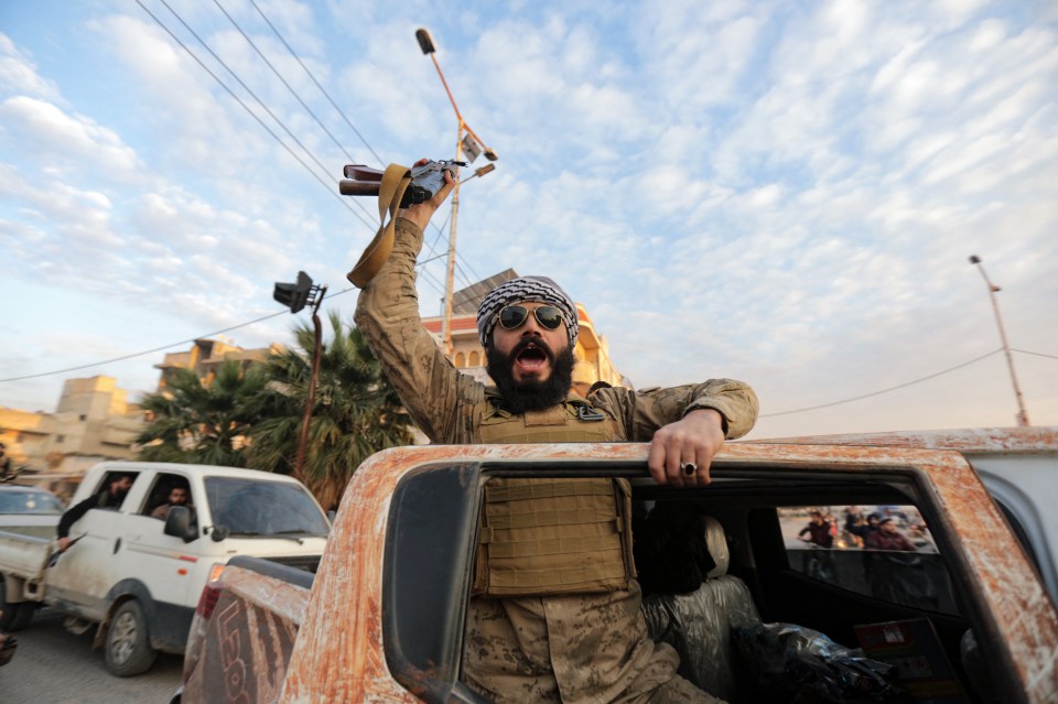 A Syrian anti-government fighter cheers as he enters the west-central city of Hama