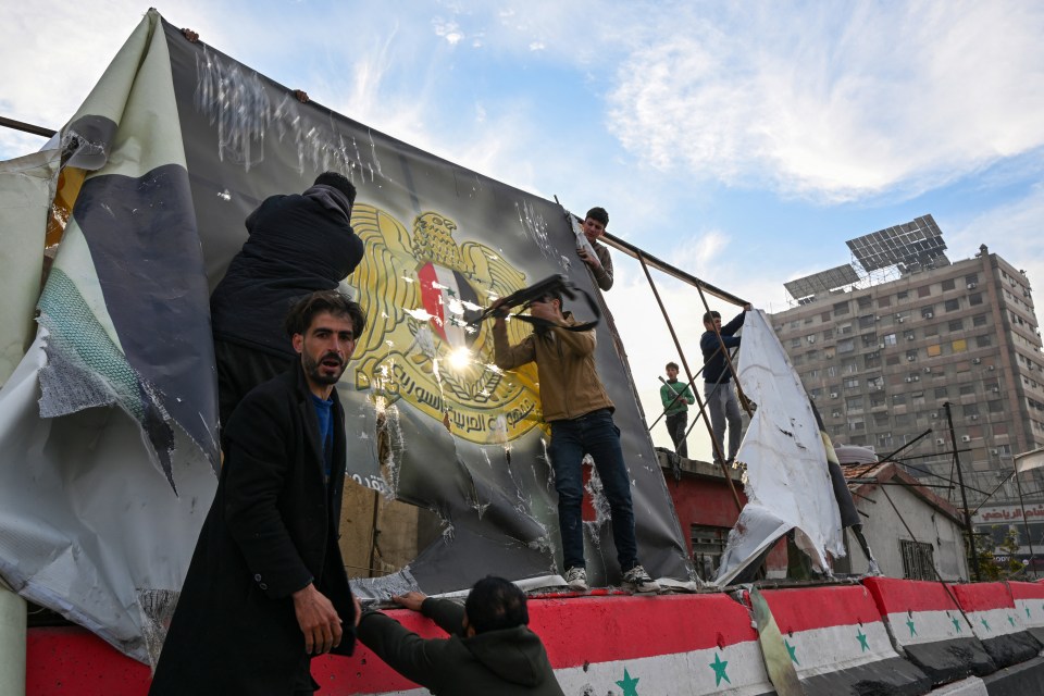 People remove a government banner in Damascus as the government was overthrown